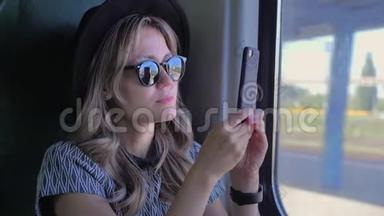 戴帽子的白人女孩坐火车旅行。 在移动智能手机上拍摄大自然的照片。 慢动作关闭